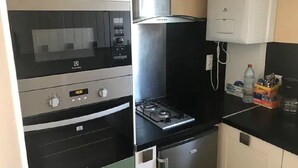 A compact kitchen with a built-in oven, microwave, and gas stove. - Feet in the water  (Langrune-sur-Mer)