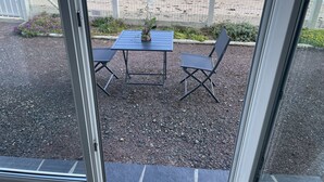 A patio with a table and chairs, a decorative plant, and a view of the beach and ocean. - Feet in the water  (Langrune-sur-Mer)