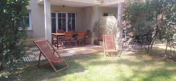 Eine Terrasse mit Tisch und Stühlen, umgeben von viel Grün und einem Holzdeck.