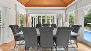 Comedor con techo de madera, ventanas amplias y vistas al exterior.