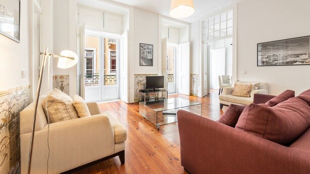 Un salon spacieux avec un canapé, un fauteuil et une table basse en verre.