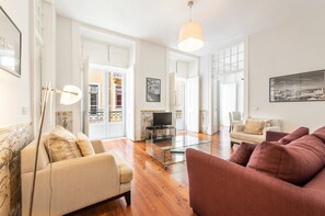 Un salon spacieux avec un canapé, un fauteuil et une table basse en verre.