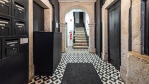 Un couloir avec des boîtes aux lettres noires portant l’inscription « Correio » et un escalier menant à l’étage supérieur.