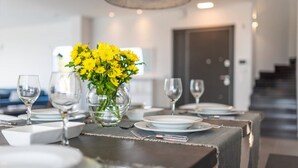Une table à manger dressée avec des assiettes, des verres et un vase rempli de fleurs jaunes.