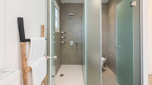 Une salle de bain moderne avec une douche à parois de verre, des toilettes et un porte-serviettes.