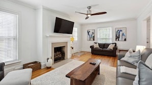 A living room with a fireplace, a sofa, a coffee table, and a television mounted on the wall.