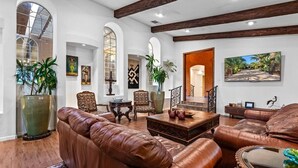A spacious living room with leather sofas, a coffee table, and a large window with arched frames. - HUGE LUX Estate, Pool/Spa, Pickleball, Sleeps 22!
Date Grove Near Palm Springs (Thousand Palms)