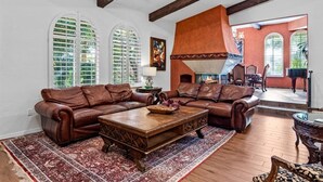 A spacious living room with leather sofas, a wooden coffee table, and a large fireplace. - HUGE LUX Estate, Pool/Spa, Pickleball, Sleeps 22!
Date Grove Near Palm Springs (Thousand Palms)
