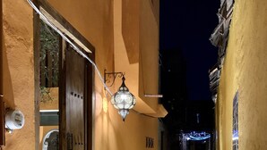 Un estrecho callejón con una puerta de madera y un farol colgante.