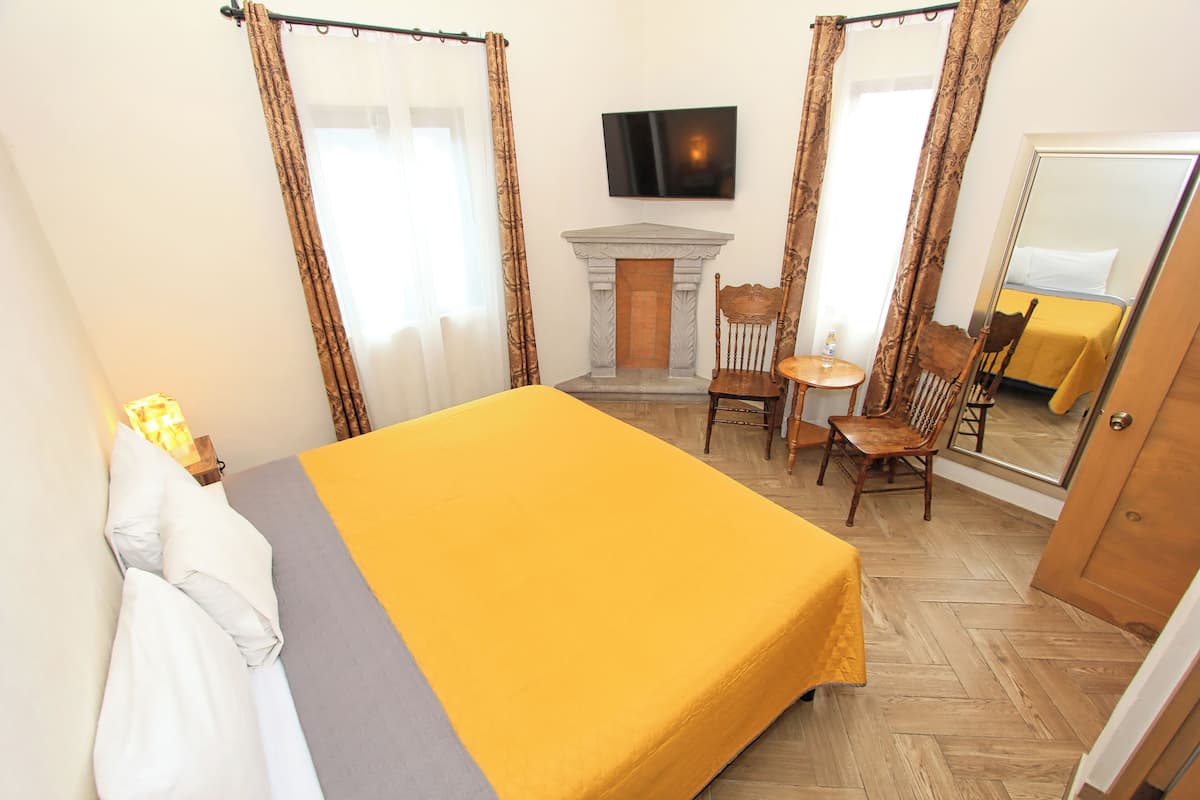 Quarto de hotel com cama, lareira, televisão e espelho.