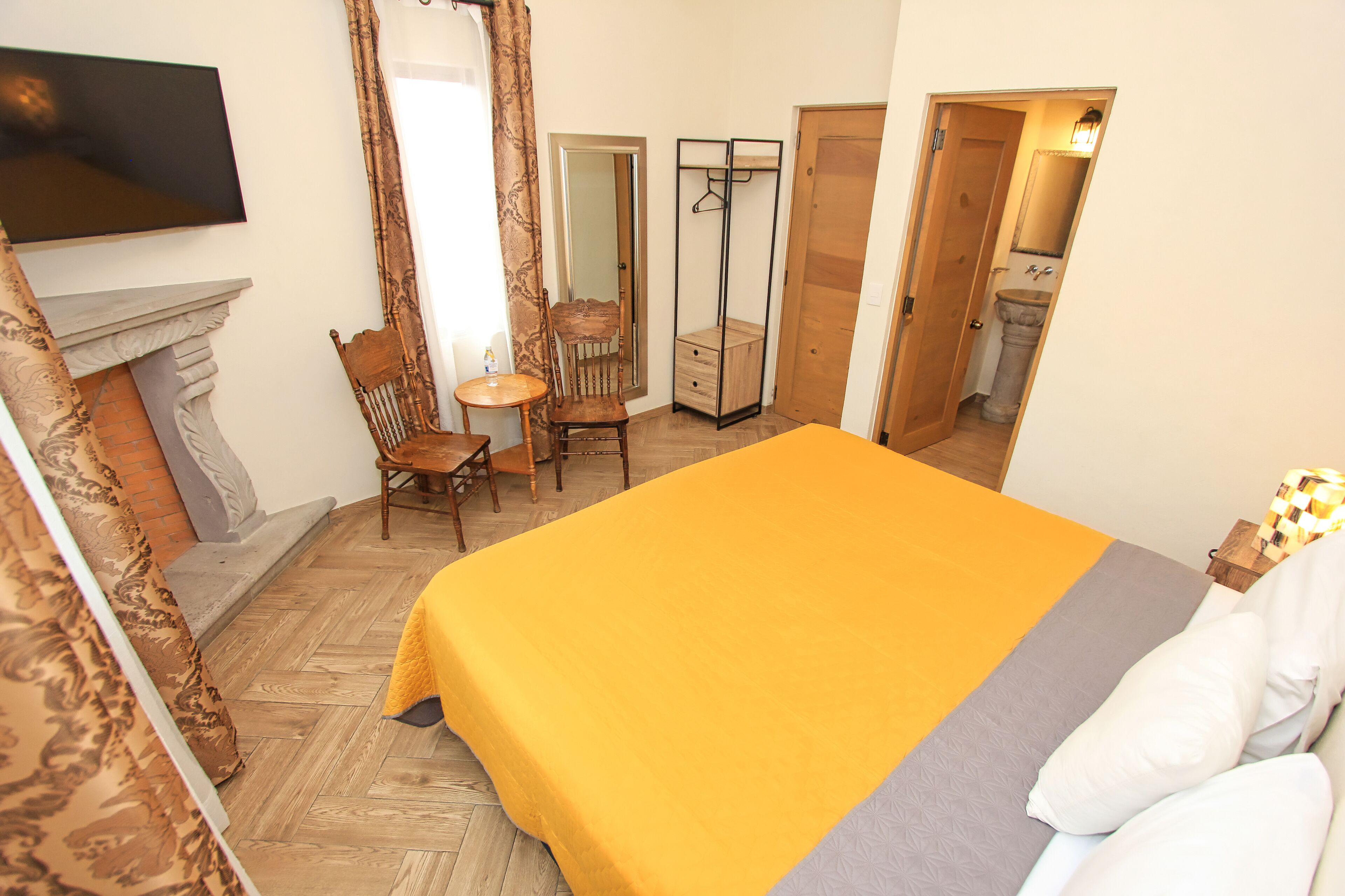 Une chambre à coucher comprenant un lit, une chaise, une petite table, un miroir et une armoire.