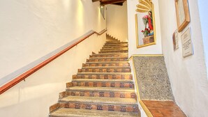 A staircase with wooden steps and a handrail, leading to a landing with a framed mirror and a small statue.
