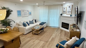 A modern living room with a sofa, coffee table, and a fireplace. - Pelicans Pointe (Indian Shores)