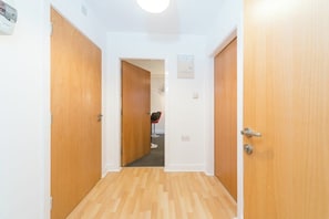 A hallway with wooden doors, a carpeted floor, and a framed picture on the wall. - Stylish Hull Apt - City Centre & Gated Parking (Hull)