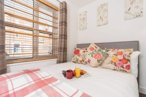 A hotel room with a bed, a breakfast tray, and a window with blinds. - Stylish Hull Apt - City Centre & Gated Parking (Hull)