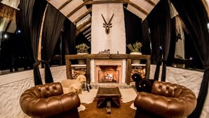 Ein gemütliches Zimmer mit Kamin, Ledersofas und einer Steinwand mit Dekoration im Hirschgeweih-Stil.