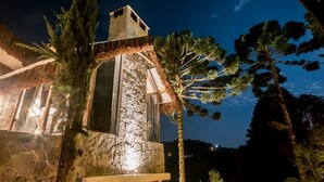 Ein Steinhaus mit einem Strohdach, umgeben von hohen Kiefern.