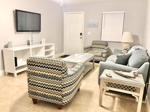 Relax in this stylish living room with a flat-screen TV, comfortable sofa, and cozy armchair.