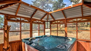A hot tub in a wooden gazebo with large windows, surrounded by a natural landscape. - Luxe Home with Hot Tub & Mountain Views (Estes Park)