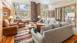 A cozy living room with a fireplace, large windows, and comfortable seating. - Luxe Home with Hot Tub & Mountain Views (Estes Park)