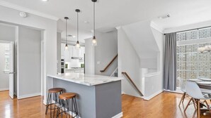 Une cuisine moderne dotée d’un îlot central, de planchers en bois et de luminaires suspendus.