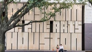Une façade de bâtiment moderne, avec des lambris en bois verticaux et un grand texte en caractères bien visibles.