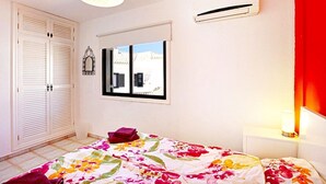 Een slaapkamer met een bed, een raam, een kledingkast en een airconditioning.