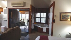 Een compacte kamer met kitchenette, badkuip en een klein zithoekje met uitzicht op de omgeving.