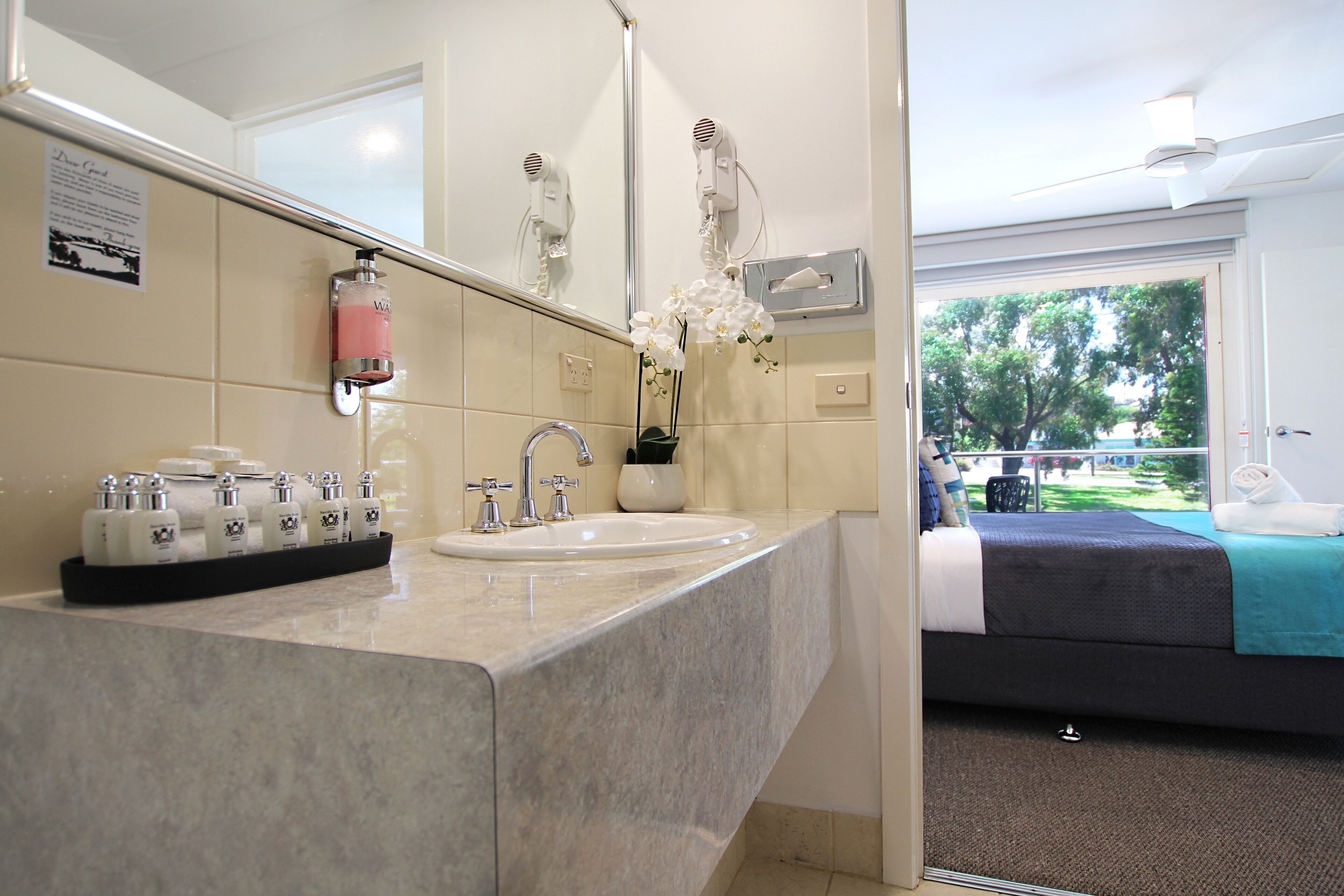 A hotel bathroom with a sink, mirror, and hairdryer.
