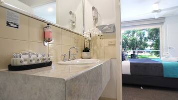 A hotel bathroom with a sink, mirror, and hairdryer.
