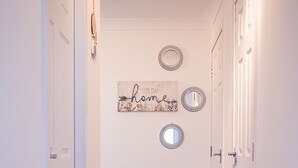 Un couloir doté d’un plancher en bois, de murs blancs et d’une pancarte d’accueil.