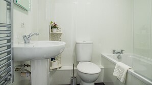 Une salle de bain moderne avec un lavabo, des toilettes et une baignoire, le tout de couleur blanche.