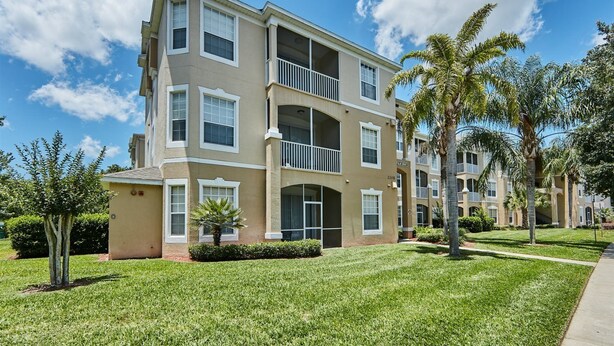 A multi-story residential building with a beige exterior, balconies, and a well-maintained lawn. - Windsor_palms_105_sp (Kissimmee)