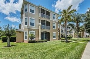 A multi-story residential building with a beige exterior, balconies, and a well-maintained lawn. - Windsor_palms_105_sp (Kissimmee)