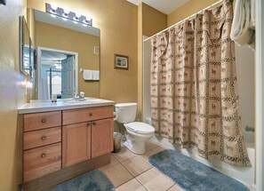 A bathroom with a wooden vanity, a toilet, and a shower curtain with animal prints. - Windsor_palms_105_sp (Kissimmee)
