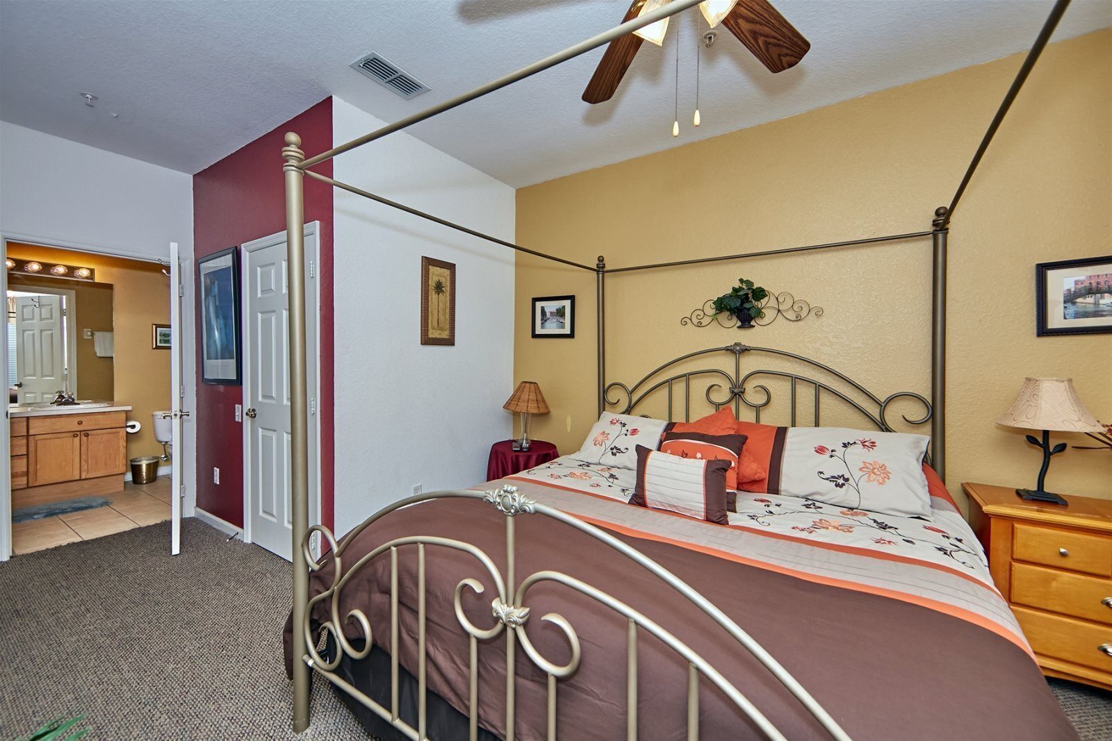 Une chambre à coucher avec un lit à baldaquin, un ventilateur de plafond, une table de chevet, une lampe et une petite table avec une lampe.