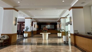 A hotel lobby with a reception desk, seating area, and a large decorative vase. - Oceanfront 2BR Condo Ilikai 1822 – Steps to Waikiki Beach | Sleeps 6 | Stunning Views (Waikiki)