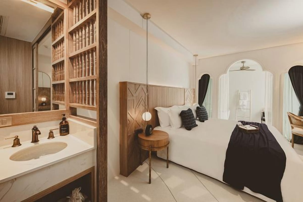 A modern bedroom with a large bed, bedside table, and a built-in wardrobe.