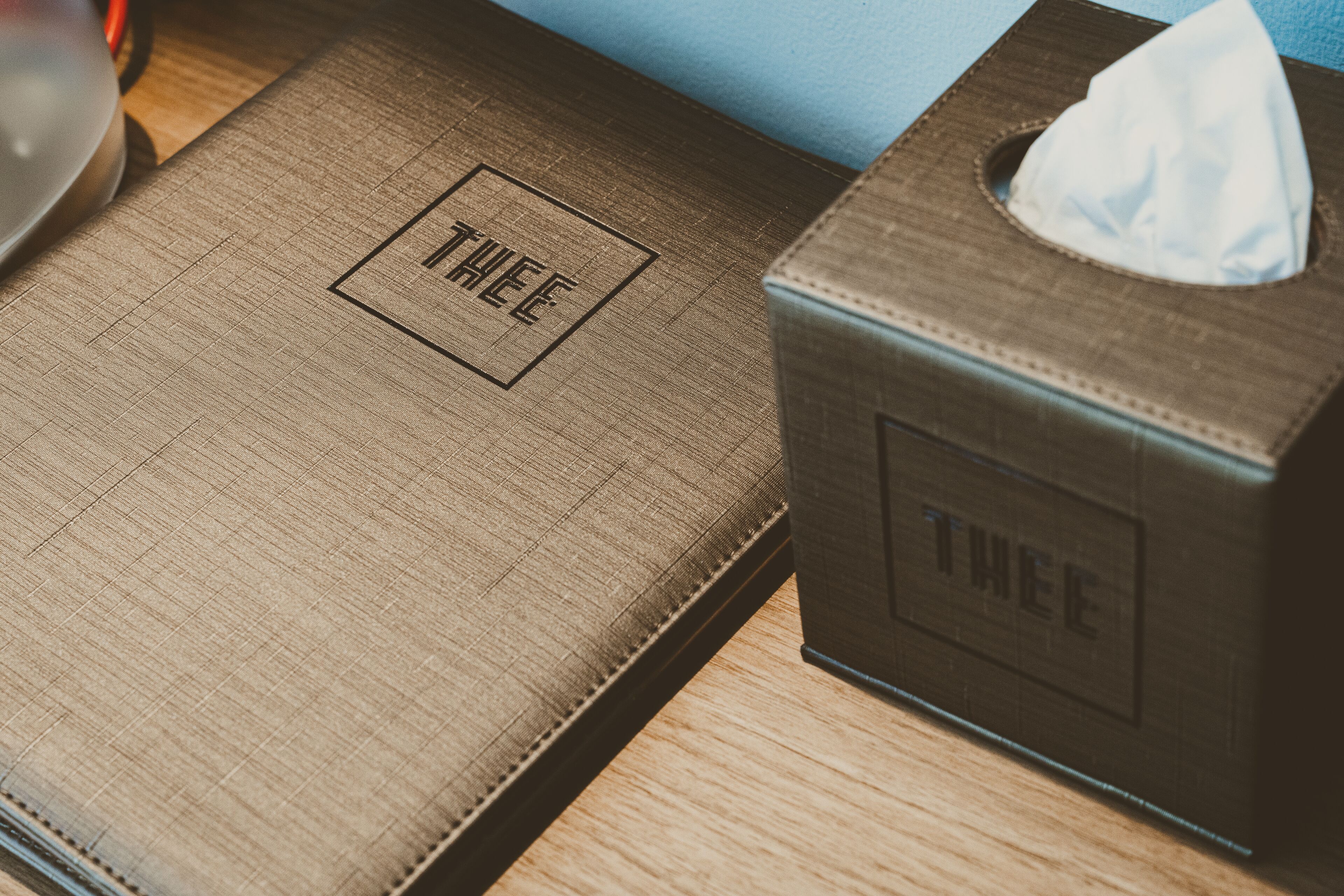 A wooden box with the word "THREE" embossed on it, next to a tissue box.