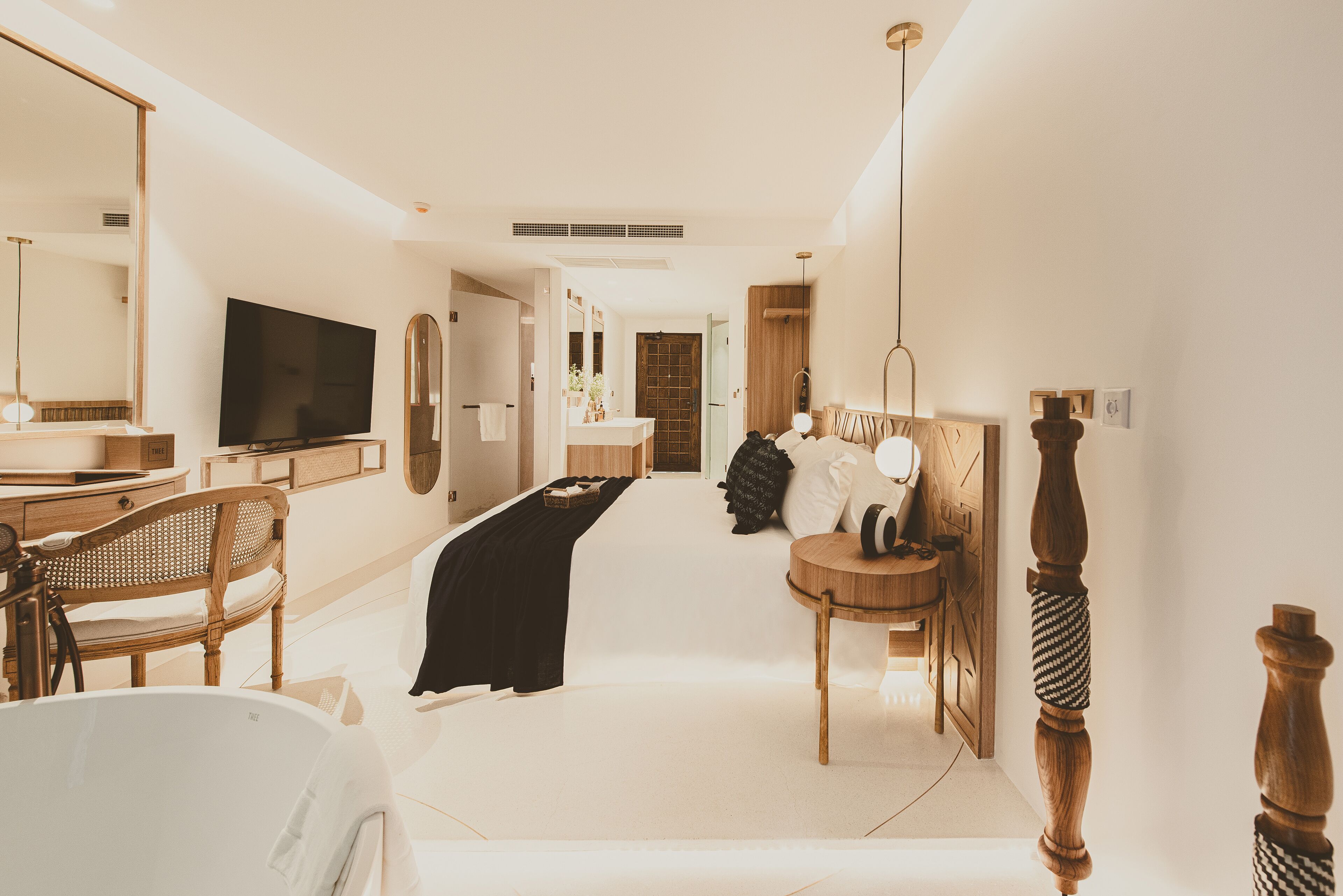Una moderna camera d'hotel con un letto grande, una televisione, una scrivania con una sedia, un comò con uno specchio e un bagno con doccia e toilette.