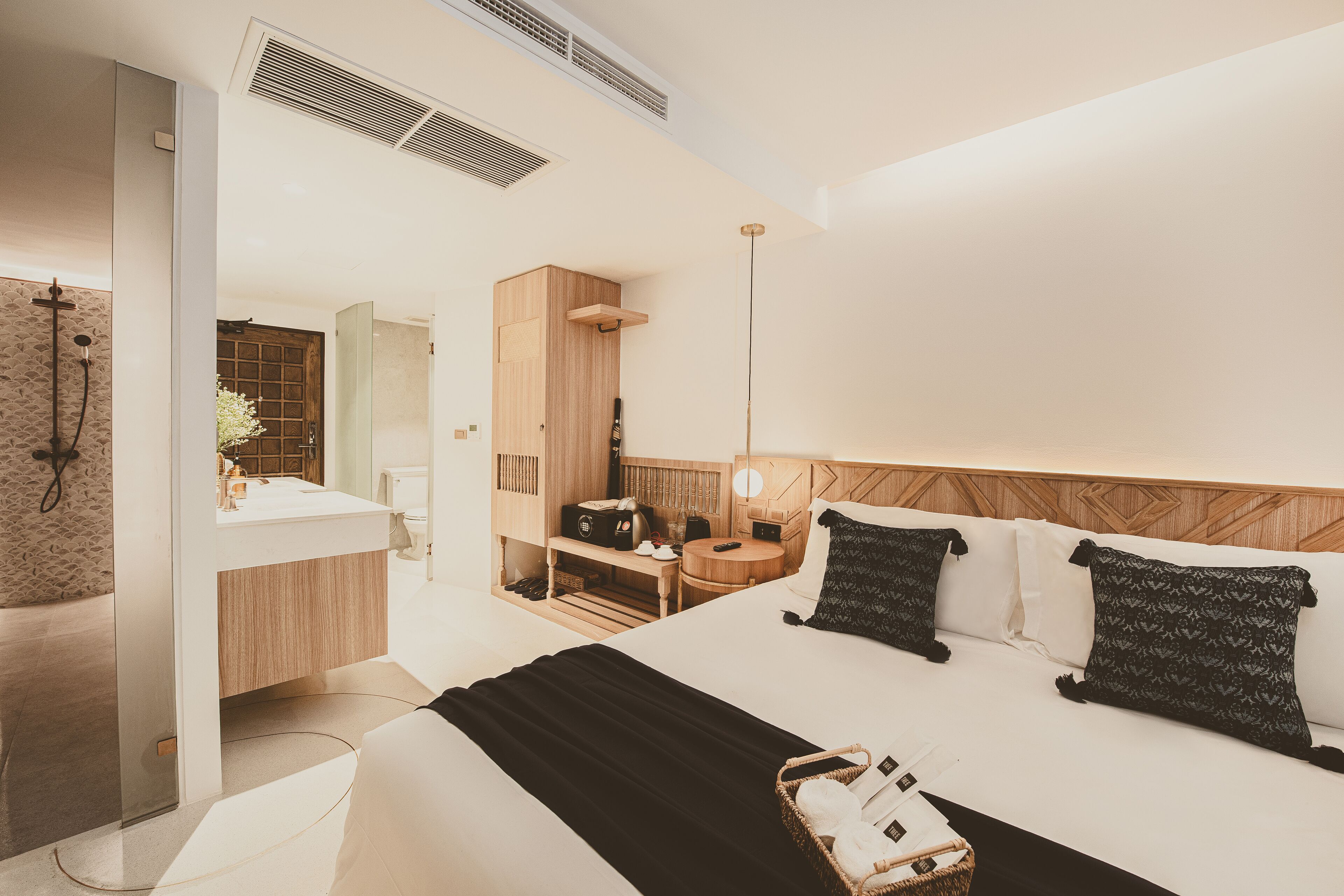 Une chambre d’hôtel moderne avec un grand lit, une table de chevet, un petit bureau, un miroir et un espace douche.