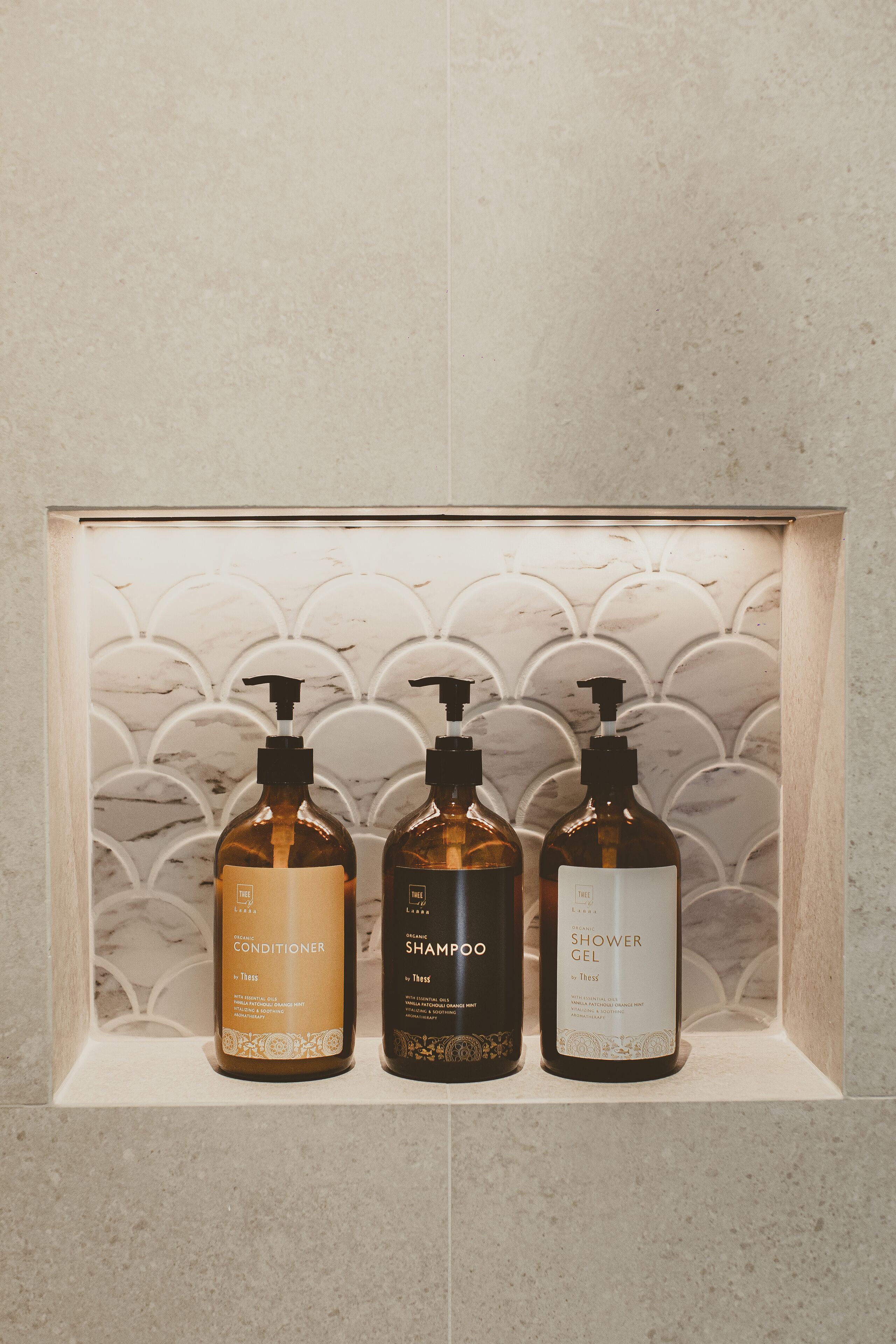 Three bottles of toiletries in a wooden box with a marble pattern background.