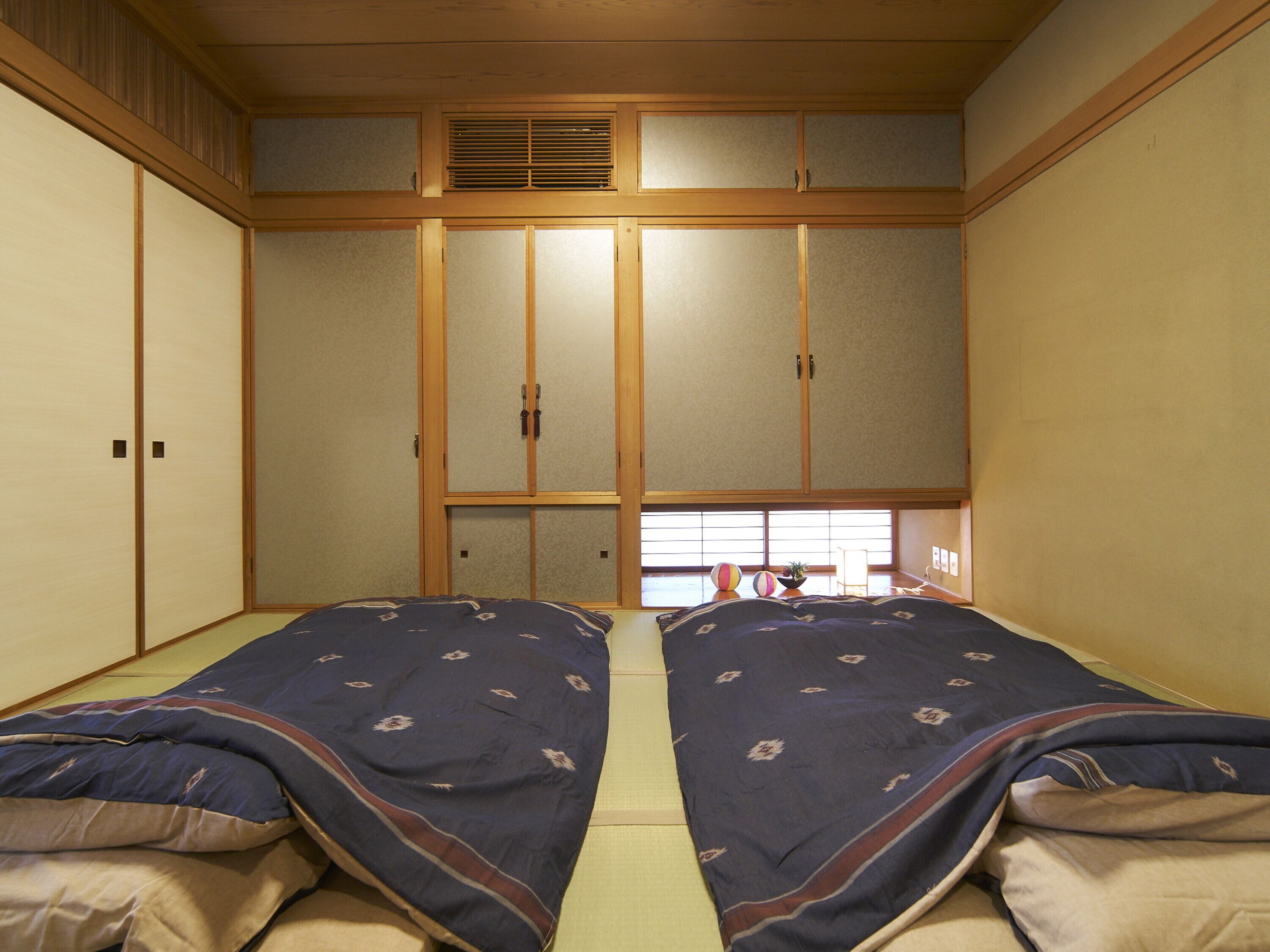Una habitación tradicional japonesa con suelo de tatami, puertas correderas y ventana con vistas.