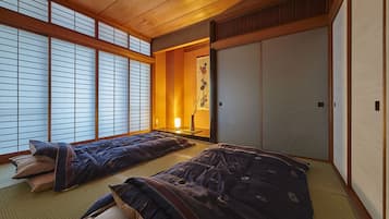 A traditional Japanese room with tatami flooring, shoji screens, and a futon bed.