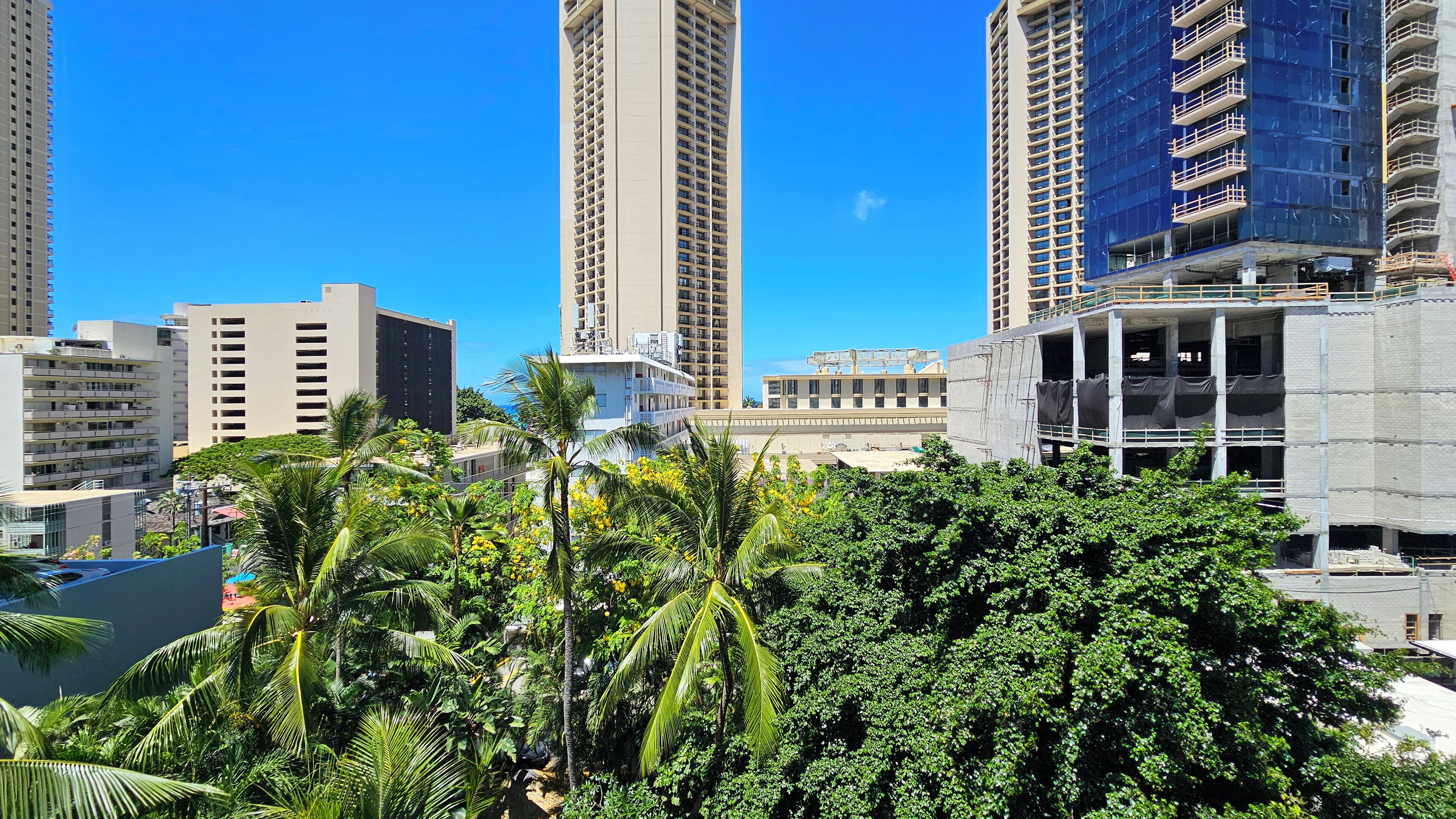 A cityscape with high-rise buildings, including a construction site with scaffolding.