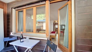 Una stanza con tavolo e sedie, un letto e una porta scorrevole in vetro che dà su un balcone.