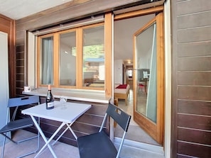 A room with a table and chairs, a bed, and a sliding glass door leading to a balcony.