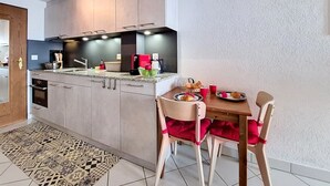 Una cucina moderna con elettrodomestici integrati, un'area pranzo con tavolo e sedie, e un tappeto decorato.