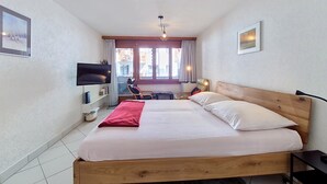 Una camera da letto con un letto, una televisione, una sedia e una finestra.