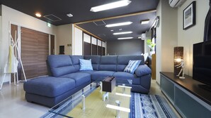 Un salon moderne avec un canapé d’angle bleu, une table basse en verre et un téléviseur à écran plat.